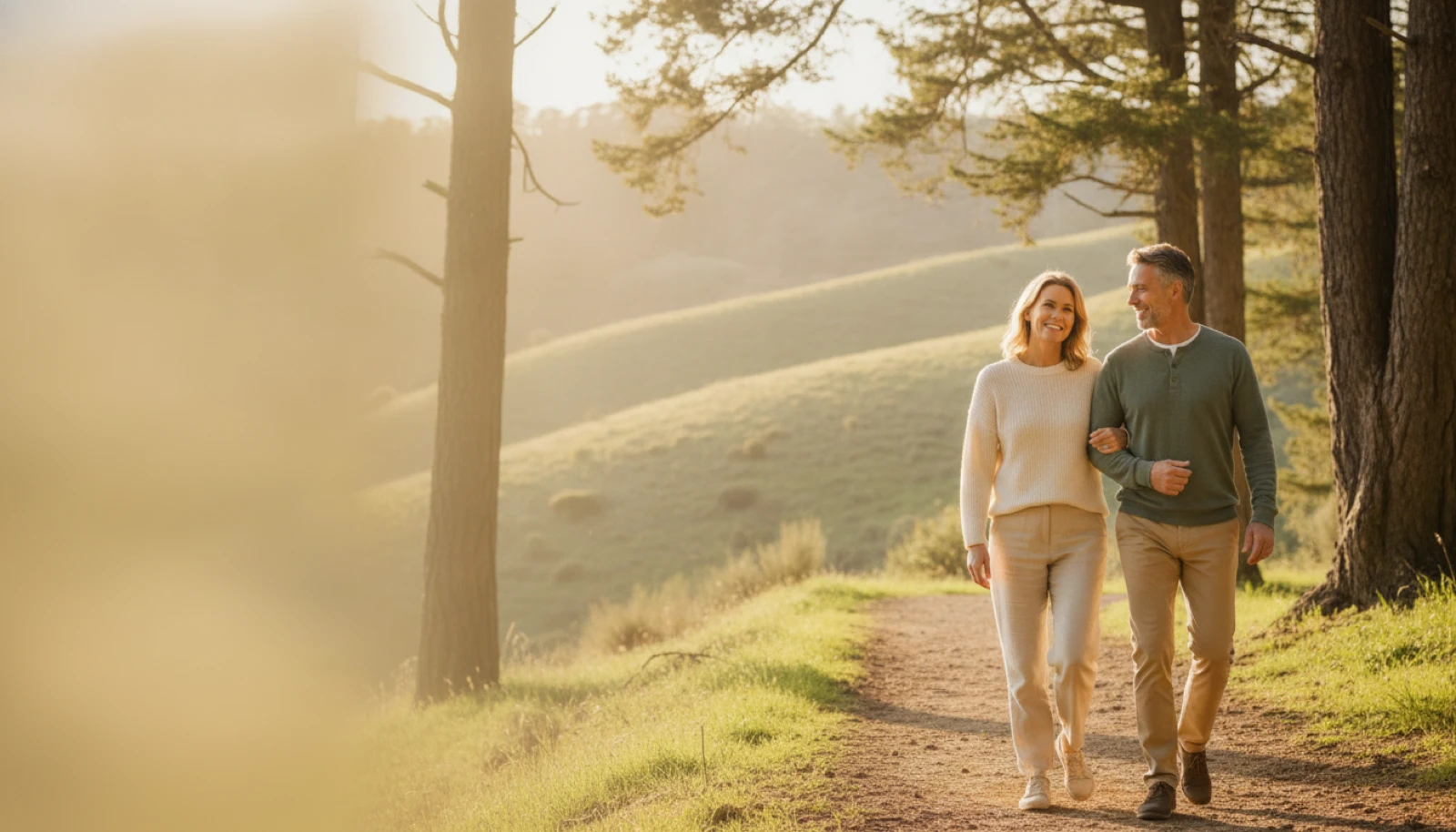 A healthy couple in their fifties walking together in warm evening light